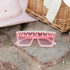 A pair of pink, square-shaped sunglasses with rhinestone embellishments on the frame.